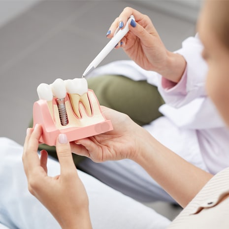 High angle view of unrecognizable young woman holding tooth model during consultation in dentists office.