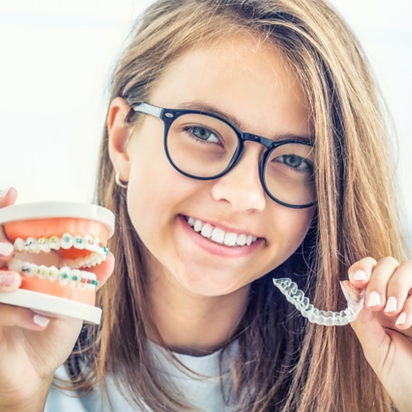 Dental invisible braces or silicone trainer in the hands of a young smiling girl.